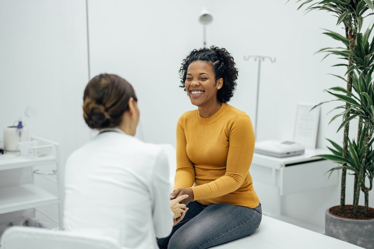 Excited woman happy to hear good news from a doctor holding hands and smiling at private practice