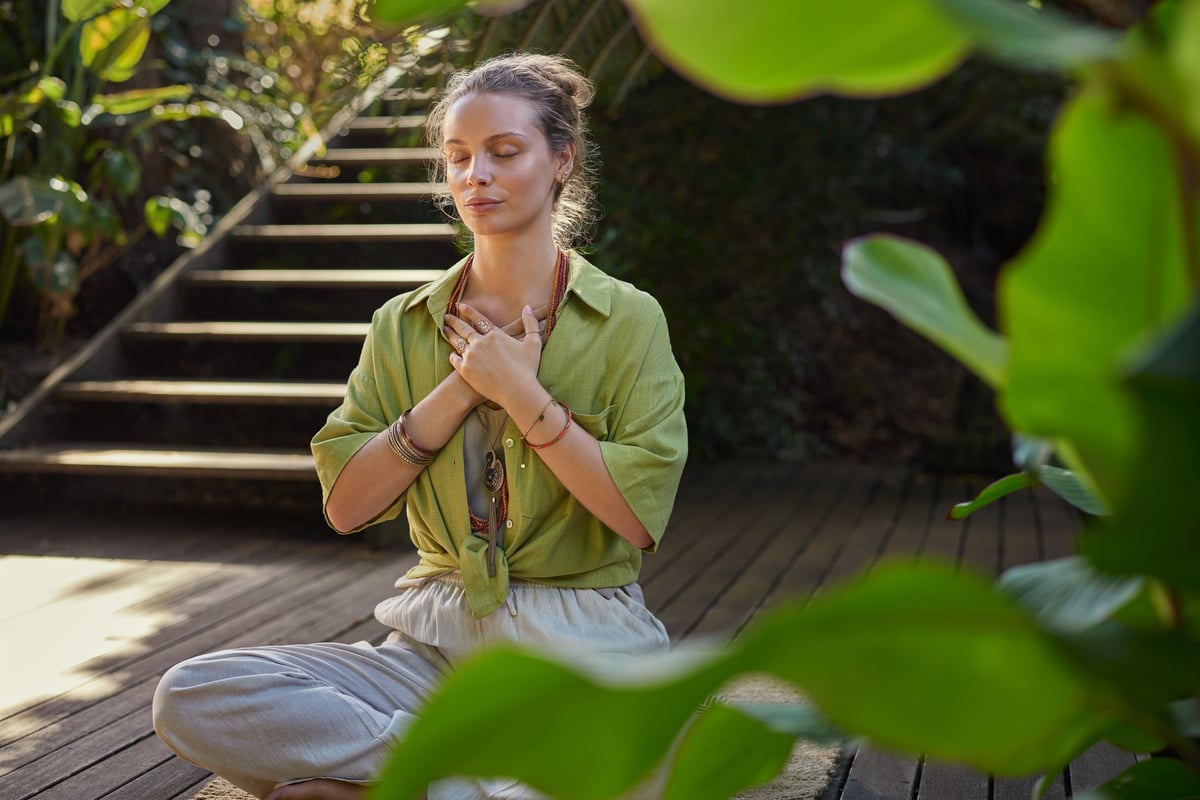 Peaceful woman meditating, hands over her heart, expressing gratitude and mindfulness, connecting with emotions during a reflective moment